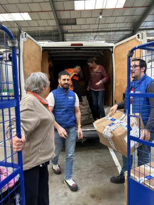 Des bénévoles et collaborateurs déchargent des cartons d’un camion dans un entrepôt, dans le cadre d’une opération de solidarité logistique.