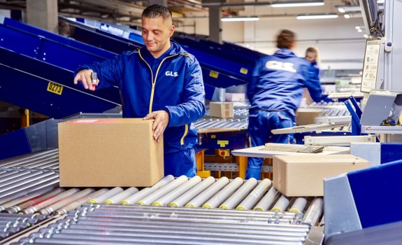 Employees sort and scan parcels on a conveyor belt