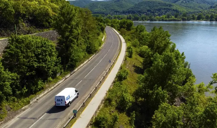 Delivery van driving on road in mountains next to lake